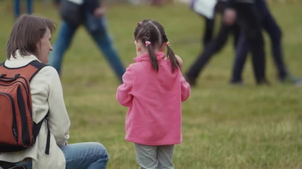 SAINT PETERSBURG, RÚSSIA - JUNHO 24, 2017: Menina conversa com a mãe e brinca com boneca na grama no festival lotado — Vídeo de Stock