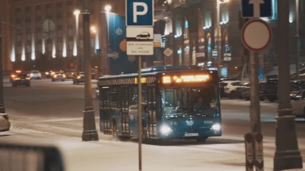 Kék utasszállító busz tutajozás éjszakai város utca, esik a hó — Stock videók