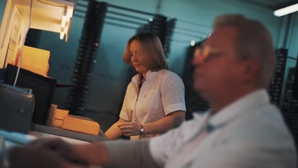 Woman in white robe take plastic tray of table and walk away in laboratory — Stock Video