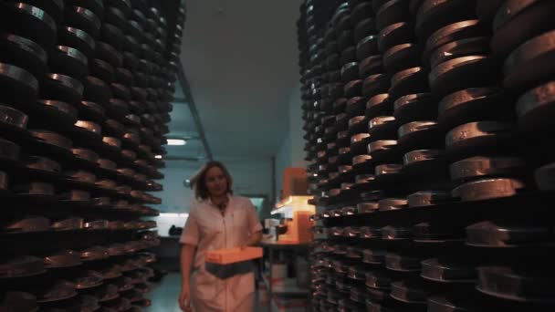 Vrouw met oranje doos wandelingen naar rack met stapels van metalen schijven — Stockvideo
