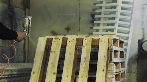 Pracownik przy użyciu aerografu do malowania drewnianych palet biały o warsztatów — Wideo stockowe
