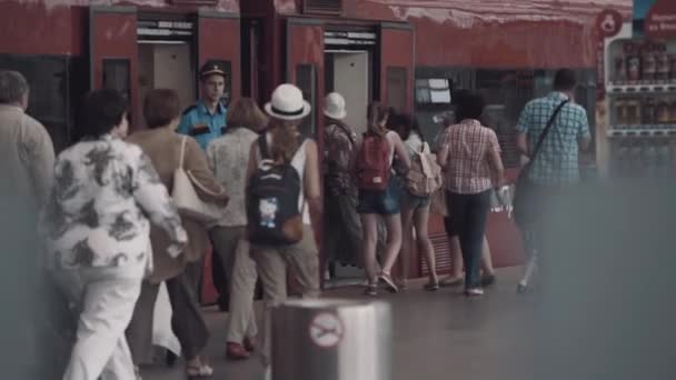 Люди туристы толпа входит красный поезд открытых дверей на станции — стоковое видео