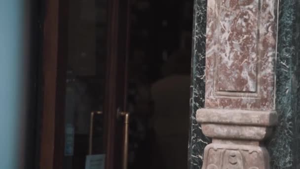 건물 화강암 벽에 문 밖으로 산책 하는 여자 — 비디오