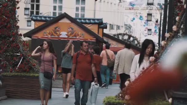 Zomer festivalterrein mensen lopen door bloemen versierd ar — Stockvideo