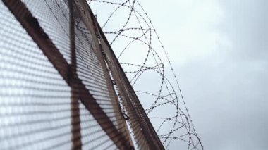 Metal elmas-mesh çit ile gri gökyüzü önünde üstte dikenli tel çit