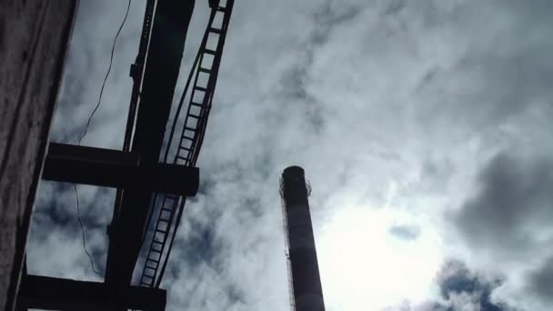 Power plant pipe silhouette in front of cloudy blue sky on sunny day — Stock Video