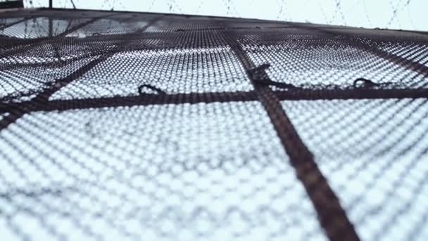Kovové plombovací plotu s ostnatým drátem nahoře před šedé obloze — Stock video