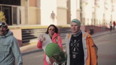 Snowboard sokakta yürümek ve kamera röportaj vermek. Erkekler bir