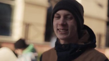 Genç adam snowboard Caddesi ve vermek üzerinde yürümek mutlu ben röportaj
