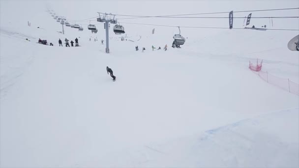 Snowboarder saltar sobre trampolim na montanha nevada. Concurso. Desafio. Gente. Estância de esqui — Vídeo de Stock