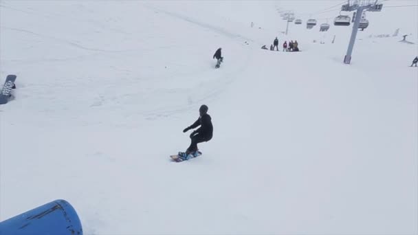Snowboardåkare hoppa på studsmatta gör stunt på snötäckta berg. Tävling. Utmaning. Personer. Ski resort — Stockvideo