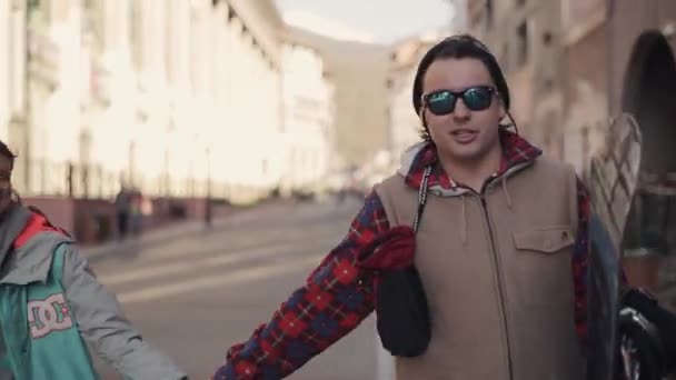 Молодая влюбленная пара сноубордистов гуляет по улице и дает интервью — стоковое видео