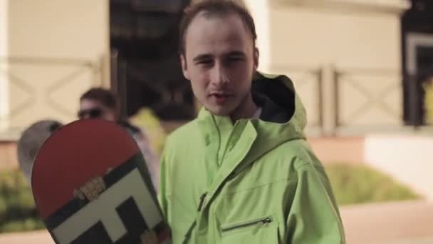 Jovens snowboarders caminham na rua e dão entrevista na câmera . — Vídeo de Stock