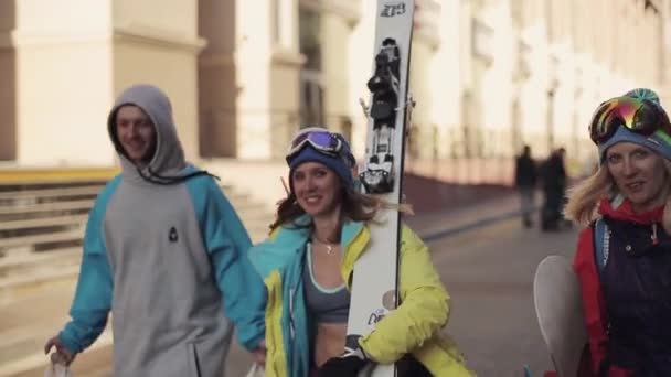 Snowboarders walk on street and give interview in camera. Smile. — Stock Video