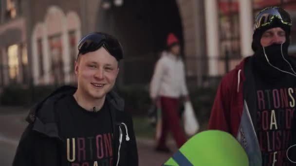 Jeune snowboarder avec un ami marcher dans la rue et donner une interview — Video