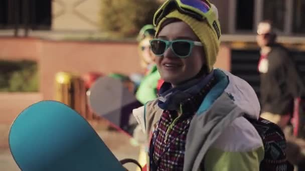 Ragazza snowboarder in cappello giallo camminare sulla strada e rilasciare intervista — Video Stock