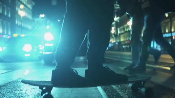 Skateboarder man feet rides across night city road crosswalk — Stock Video