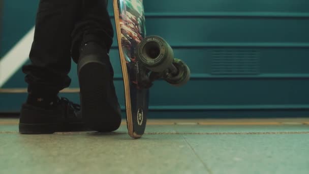 Skrzyżowane nogi facet z longboard stojący na stacji metra — Wideo stockowe