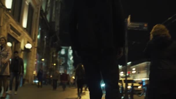 Скейтбордист в черной толстовке едет на переполненном ночном городском сиде — стоковое видео