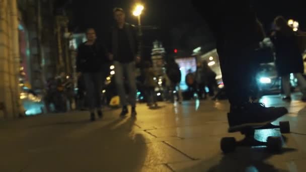 Skater facet w czarnym kapturem jeździ na noc zatłoczone miasto sid — Wideo stockowe