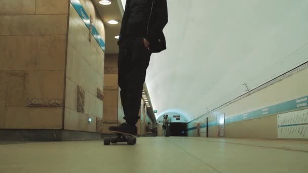 Guy rides longboard at empty underground metro station — Stock Video