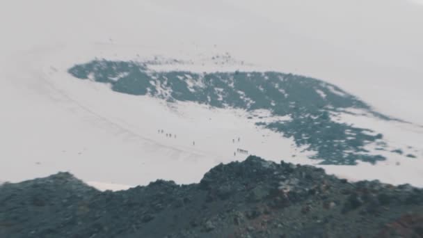 高さの雪に覆われた山の斜面の上を歩く人アルピニスト観光客 — ストック動画
