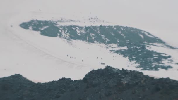 高雪の山丘の中腹を歩いて人々 アルピニスト観光客 — ストック動画