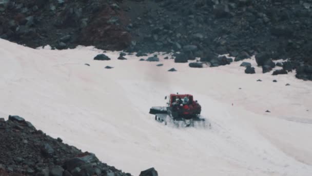 Snowcat caterpillar machine with passangers rides on mountain slope — Stock Video