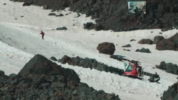 Snowcat caterpillar machine with tourists rides on mountain slope — Stock Video