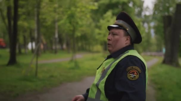 Pracownik policji ruchu, pobity i zmęczony, idąc przez park miejski — Wideo stockowe