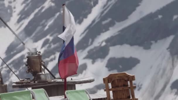 Meisje op sneeuw overdekte berg camping met Russische vlag wapperend — Stockvideo