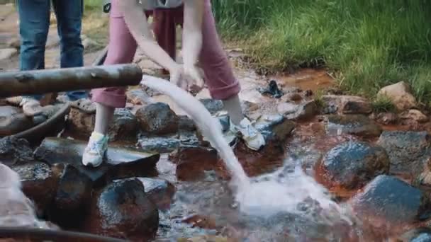 Woman drinks water with hands from metal pipe wellspring — Stock Video