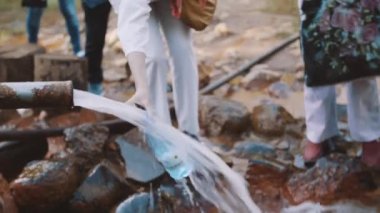 Yaşlı kadın metal boru kaynak plastik şişe içine su dökülen