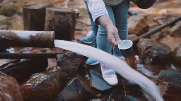 Mujer anciana llenando taza de plástico con agua del manantial de camino de montaje — Vídeo de stock