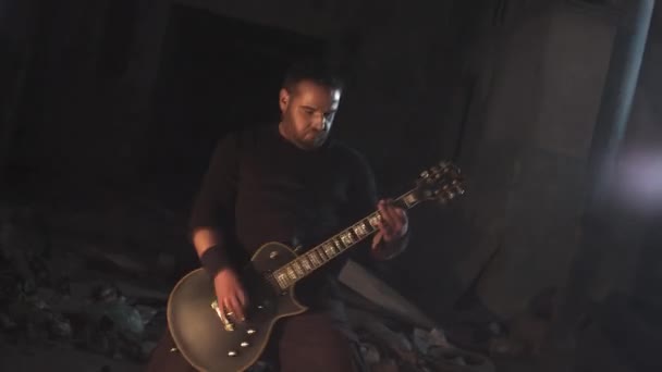Музыкант агрессивно играет на металлической гитаре в заброшенном здании — стоковое видео