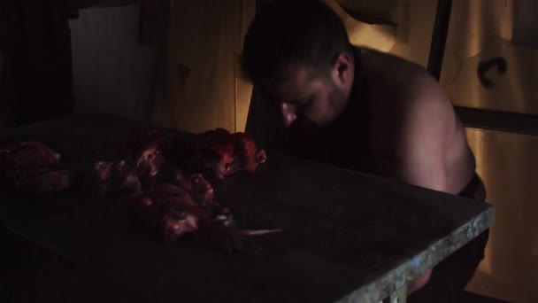 Homme fou couvert de sang dans un bâtiment abandonné riant et hachant de la viande — Video