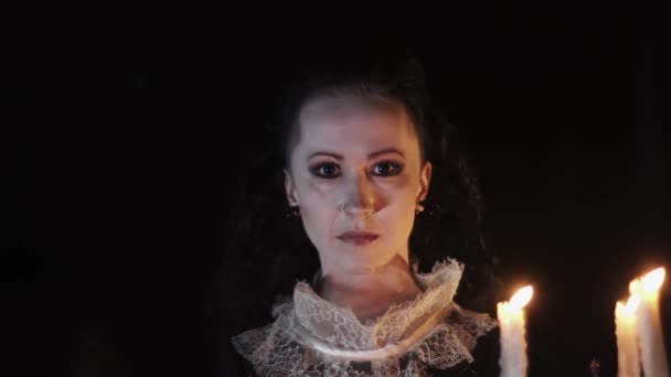 Portret de femeie în rochie victoriană holbându-se în cameră întunecată cu candelabru — Videoclip de stoc