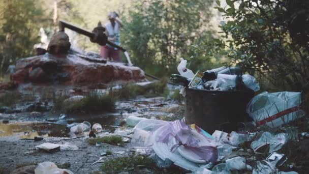 Σωρό από σκουπίδια μπροστά από μεταλλικό σωλήνα ανεξάντλητη πηγή στο δάσος μονοπάτι στο βουνό — Αρχείο Βίντεο