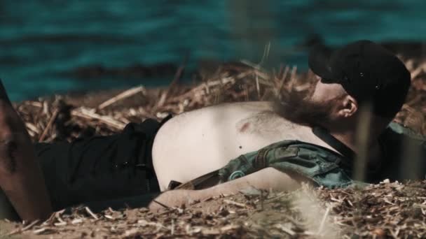 Şişman çıplak göbek ile göl kıyısında güneşlenerek motorcu adam sakallı — Stok video