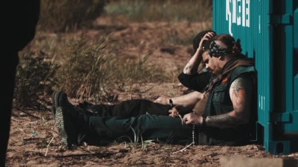 Grupo de motociclistas sentados en tierra apoyados en contenedores de carga — Vídeos de Stock