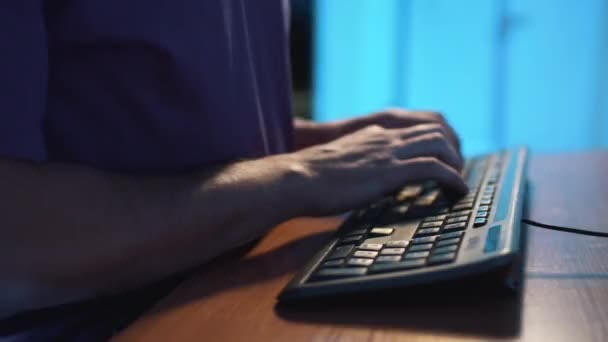 Kamera obraca się wokół rąk człowieka w fioletowym t-shircie wpisując na czarnej klawiaturze — Wideo stockowe