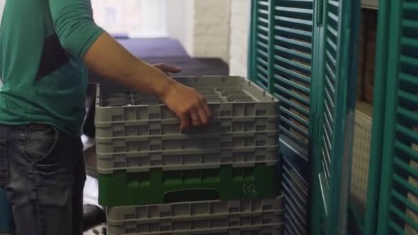 Man wearing green sweater is putting grey plastic baskets on dark table. — Stock Video