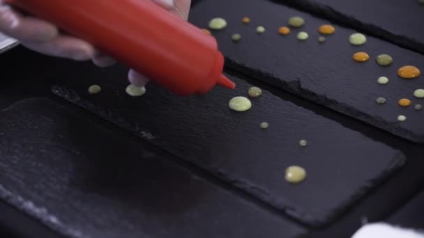 Decoration of black rectangular plate by putting drops by red plastic bottle — Stock Video