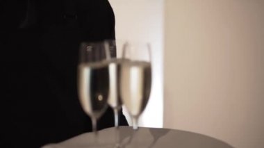 Siyah tepsideki garsonun bulanık manzarası ve üç kadeh şampanya.