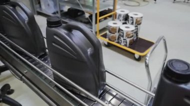 Fabrikada hareket eden taşıyıcıyla motor yağı doldurma görüntüsü.