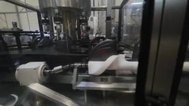 Fabrikada hareket eden taşıyıcıyla motor yağı doldurma görüntüsü.