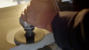Mans el granit bloğun yüzeyini cilalamak için elektrikli el cilası kullanır.