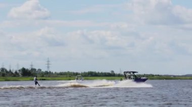 Moskova, Rusya - 12 Temmuz 2019: Sportif adam nehir boyunca giden tekneyi takip ederek su yüzeyinde yüzüyor