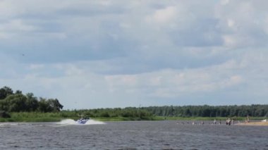 Moskova, Rusya - 12 Temmuz 2019: Sportif bir adam nehir boyunca giden tekneyi takip ederek su yüzeyine atlıyor