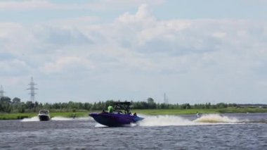 Moskova, Rusya - 12 Temmuz 2019: Sportif bir adam nehir boyunca giden küçük bir tekneyi takip ederek su yüzeyinde süzülüyor